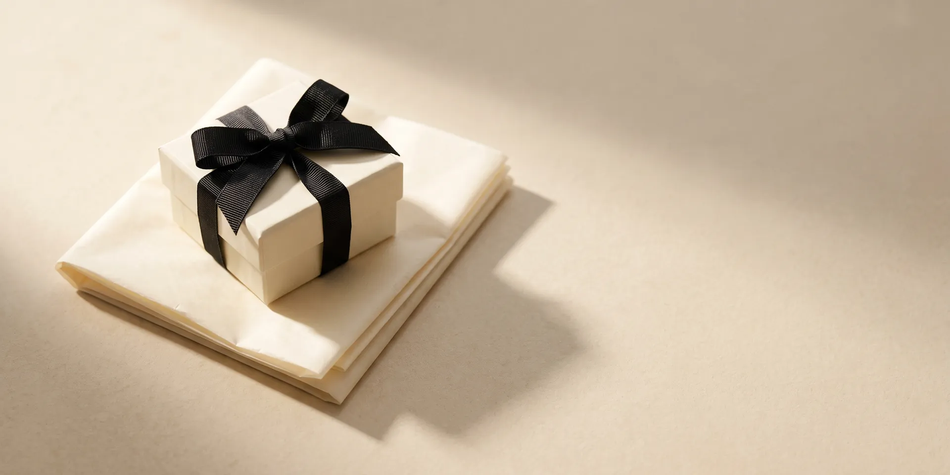 ALVANY shipping — an ivory gift box tied with black ribbon, ready to send